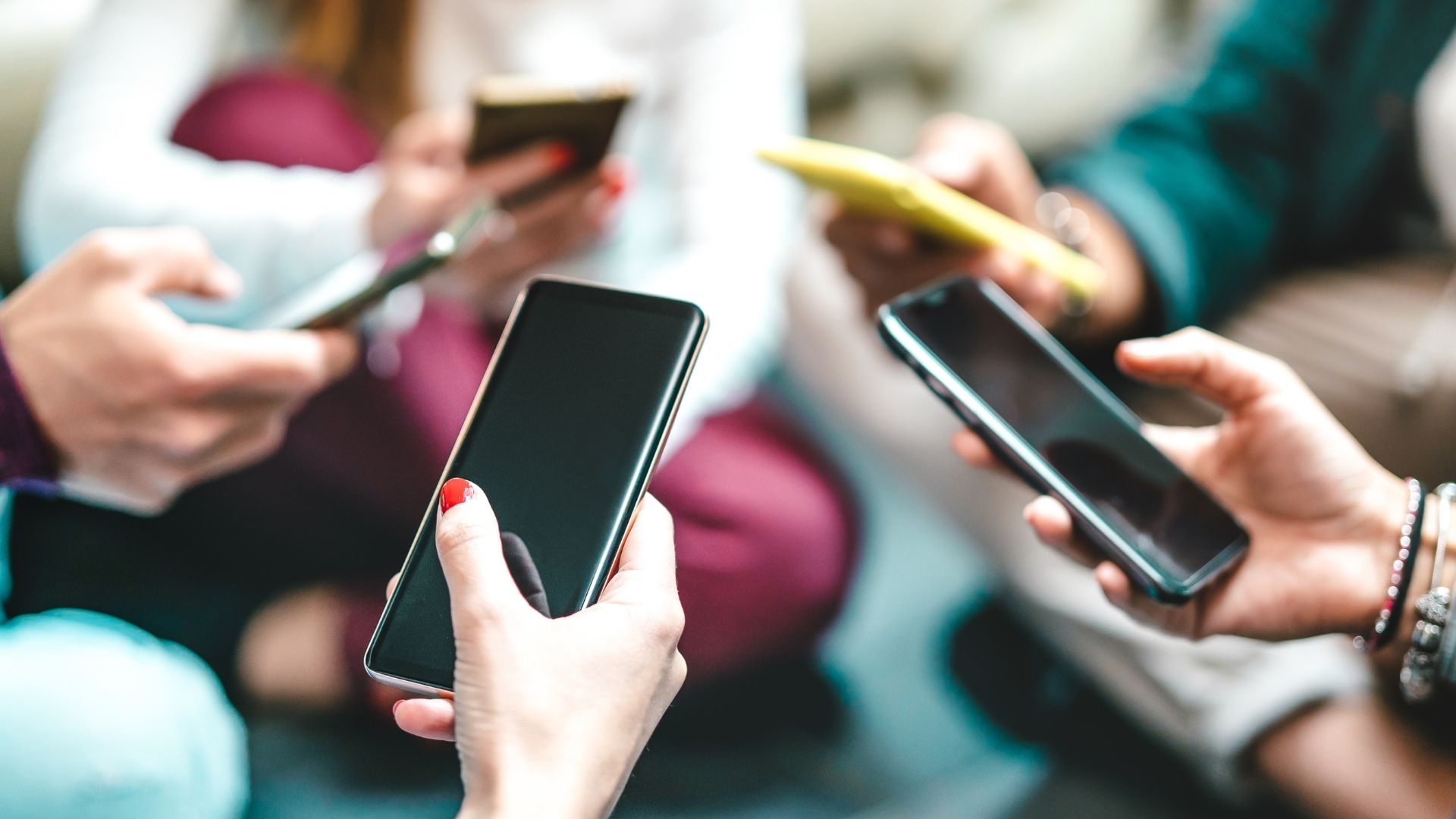 Group of people holding smartphones, focused on screens.